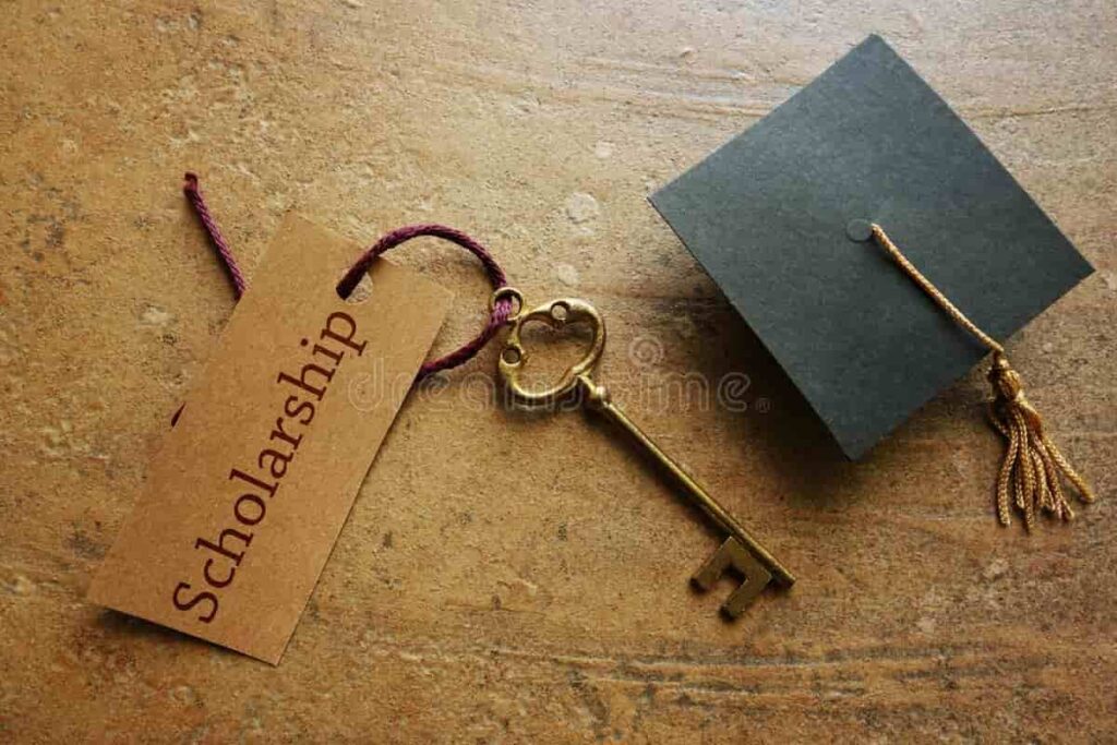 Golden key labeled βScholarshipβ beside a graduation cap, symbolizing access to education through financial aid.