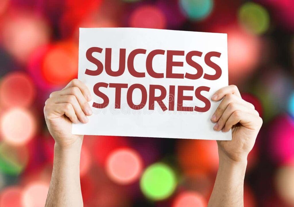 Hands holding a sign with the words Success Stories on a colorful blurred background
