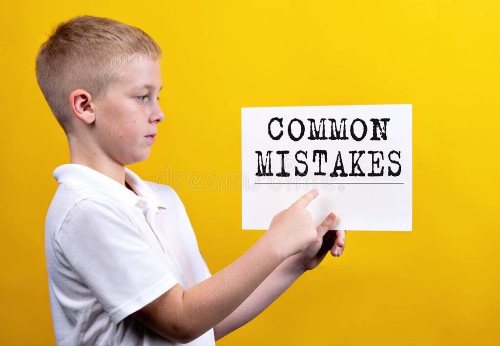 Young boy pointing at a sign that says "Common Mistakes" on a yellow background