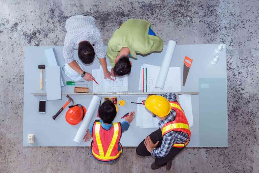 Group of construction workers wearing safety gear and helmets, discussing plans at a worksite โ representing post-study work opportunities in Ireland.