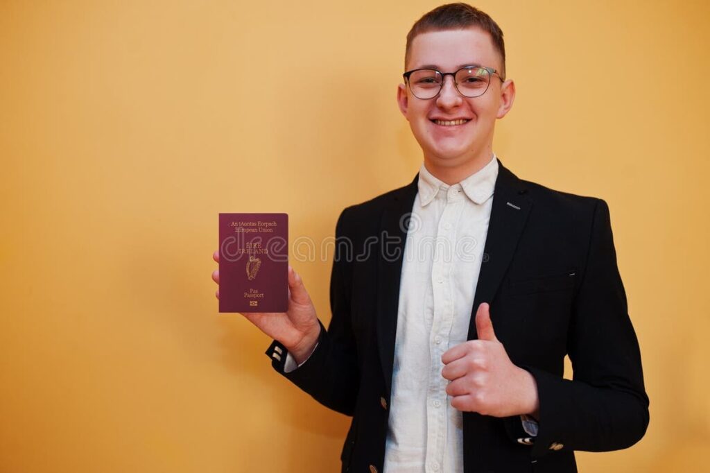 Smiling man in a suit holding a passport and giving thumbs up โ representing Ireland student visa approval.