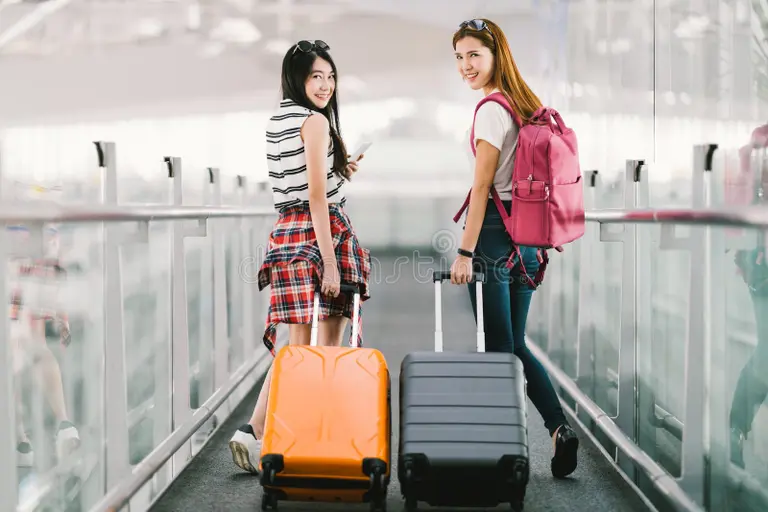 Two students with suitcases in an airport corridor—arrival week and orientation plan for Study in Singapore.