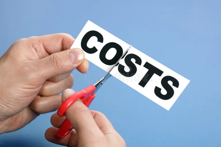 Hands cutting the word “COSTS” with red scissors on a blue background—budgeting and savings for Study in Singapore.