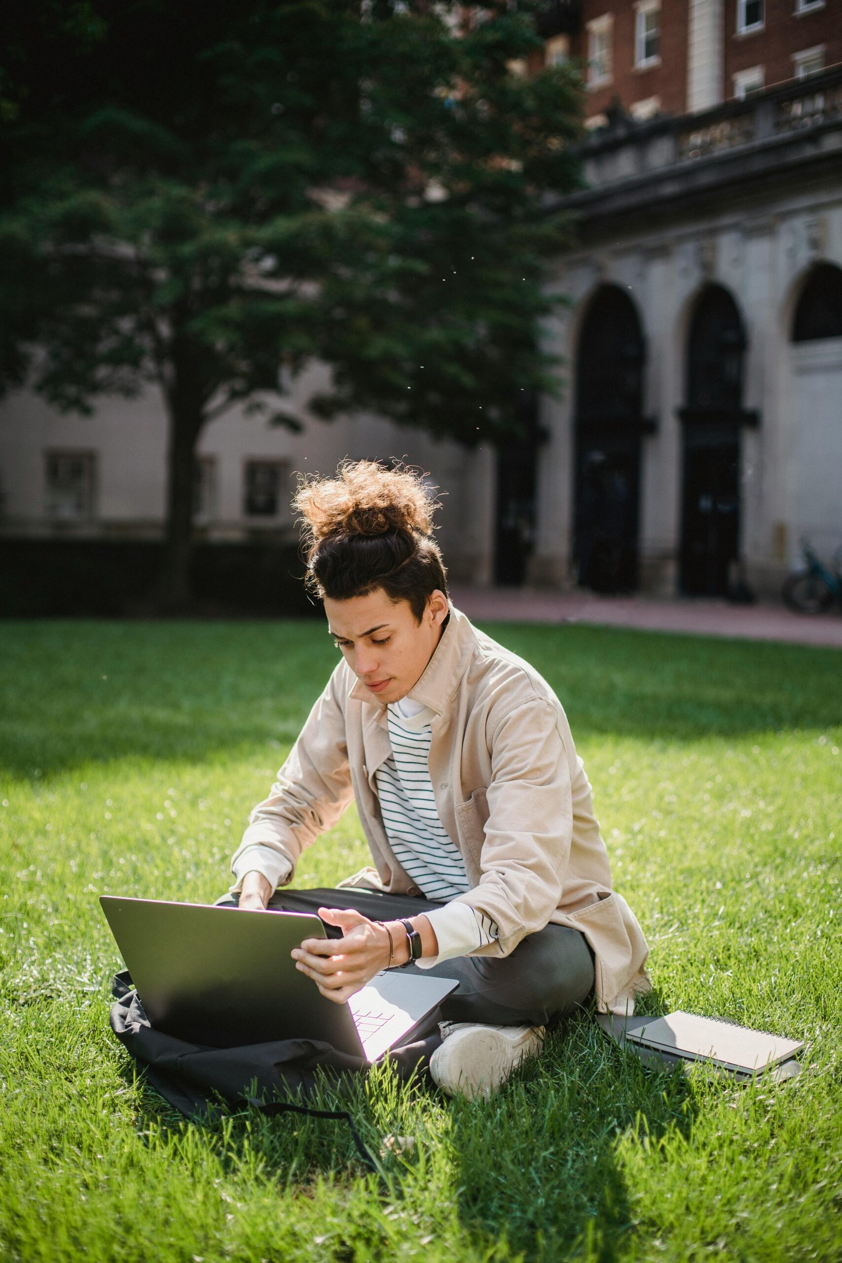 Young international student studying on a university campus lawn in New Zealand, representing modern education, study abroad lifestyle, and Study in New Zealand opportunities.