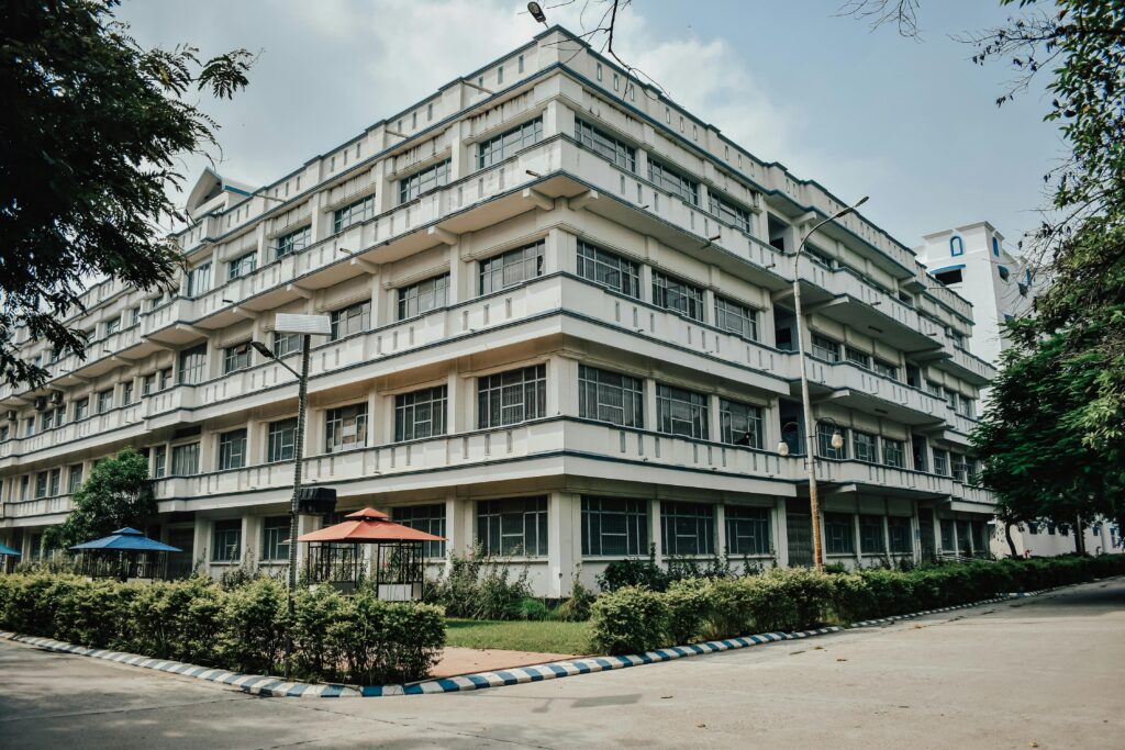 Modern white hostel building with multiple floors and glass windows on an Indian university campus, symbolizing student housing in India