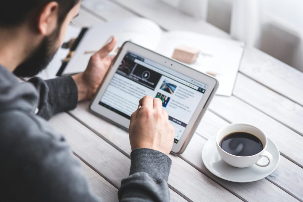 A student reading a study abroad checklist on a tablet with a cup of coffee, symbolizing focused preparation and planning.