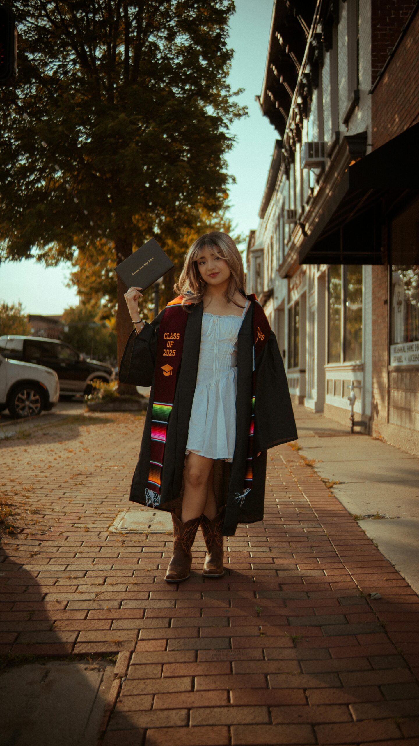 Female graduate celebrating her success outdoors, wearing a graduation gown that reads “Class of 2025,” symbolizing education and study abroad opportunities in Italy.