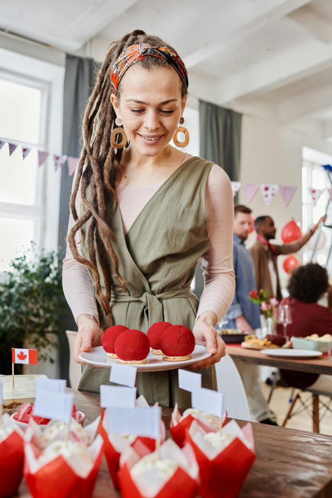 A woman enjoying Canadian food decorated with the national flag during a student gathering, representing cost of living and daily lifestyle in Canada.