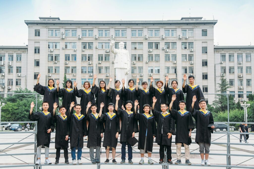 A large group of graduating medical students wearing black gowns posing in front of a university building in China — symbolizing MBBS education and essentials for studying medicine in China.