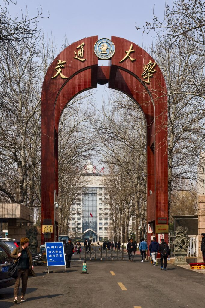 Main entrance gate of Beijing Jiaotong University with students walking on campus road, symbolizing higher education and student life in China.