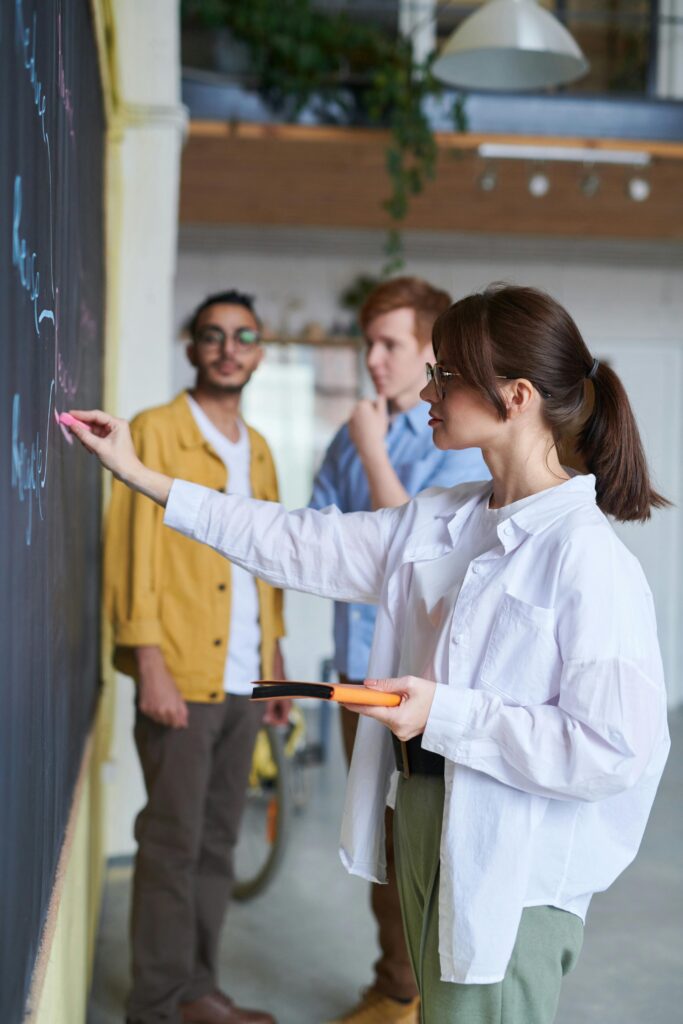 A student writing on a classroom board while others observe, symbolizing final learning insights for international students studying in Denmark.