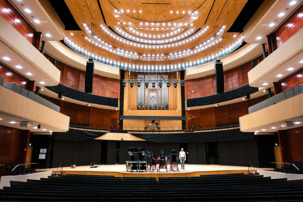 A large modern university auditorium in Finland with bright lighting and seating, representing vibrant student life and cultural events for international students.