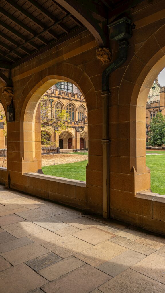 A view of an iconic Australian university campus with traditional sandstone architecture and green courtyard.