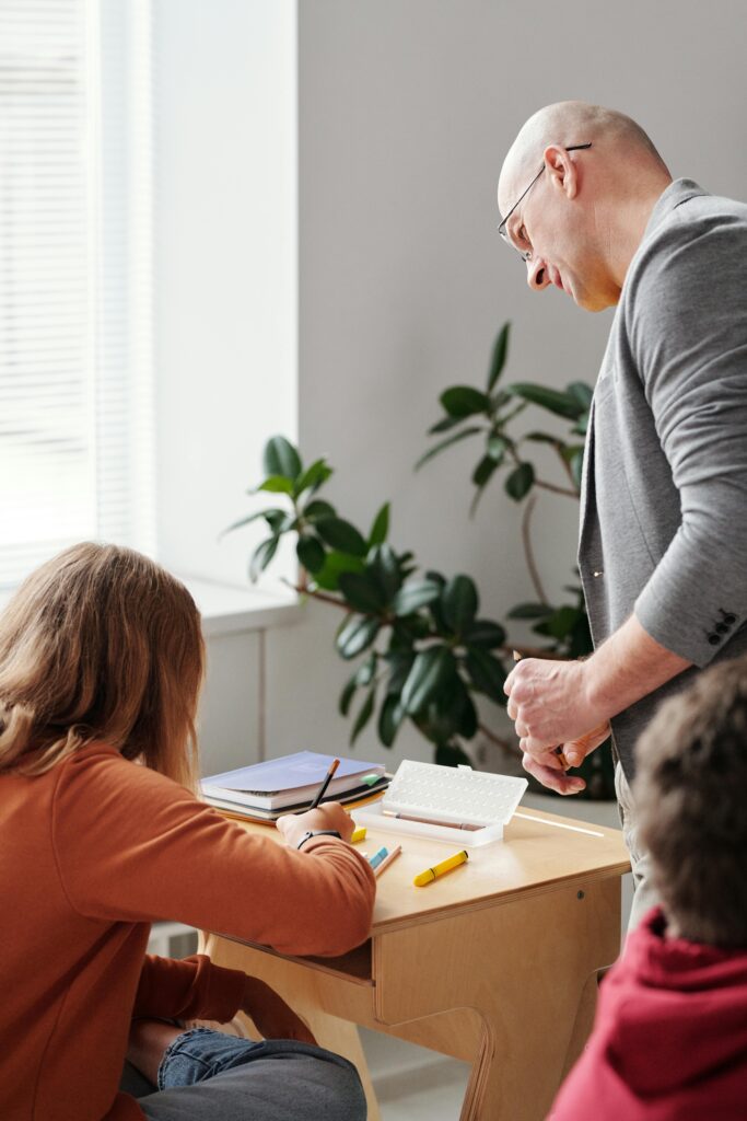 A teacher guiding a student in a classroom, representing academic and personal support services available for international students in Denmark.