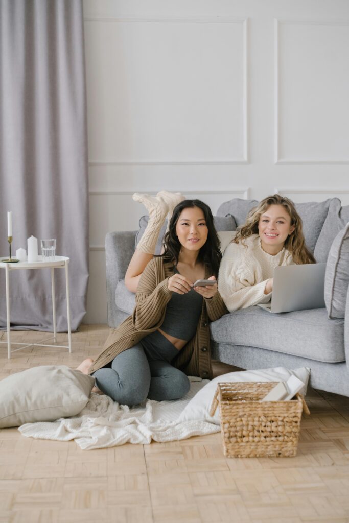 Two international students studying and relaxing in a cozy apartment, representing the comfortable and multicultural student life in Canada.