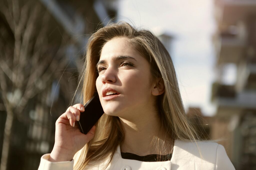 A young woman talking on a mobile phone outdoors, symbolizing communication, connection, and student queries for Study Silently’s Contact Us section.