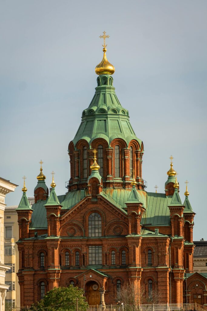 Historic Uspenski Cathedral in Helsinki, Finland photographed in daylight with its green domes and red-brick architecture.