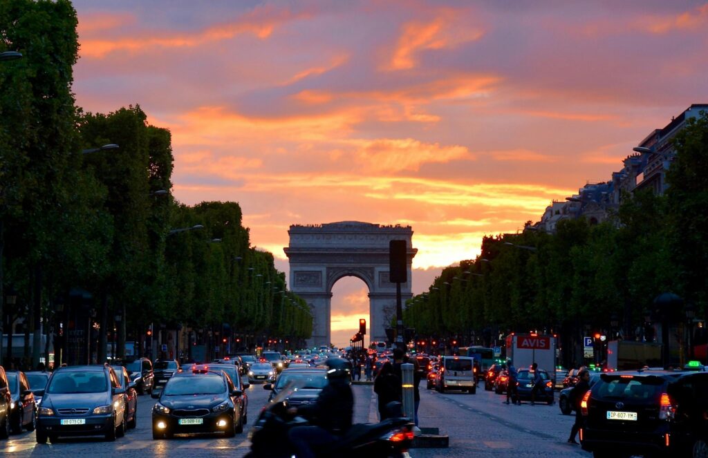 Sunset view of the Arc de Triomphe with busy Paris streets, symbolizing student entry, documentation, and admission requirements in France.