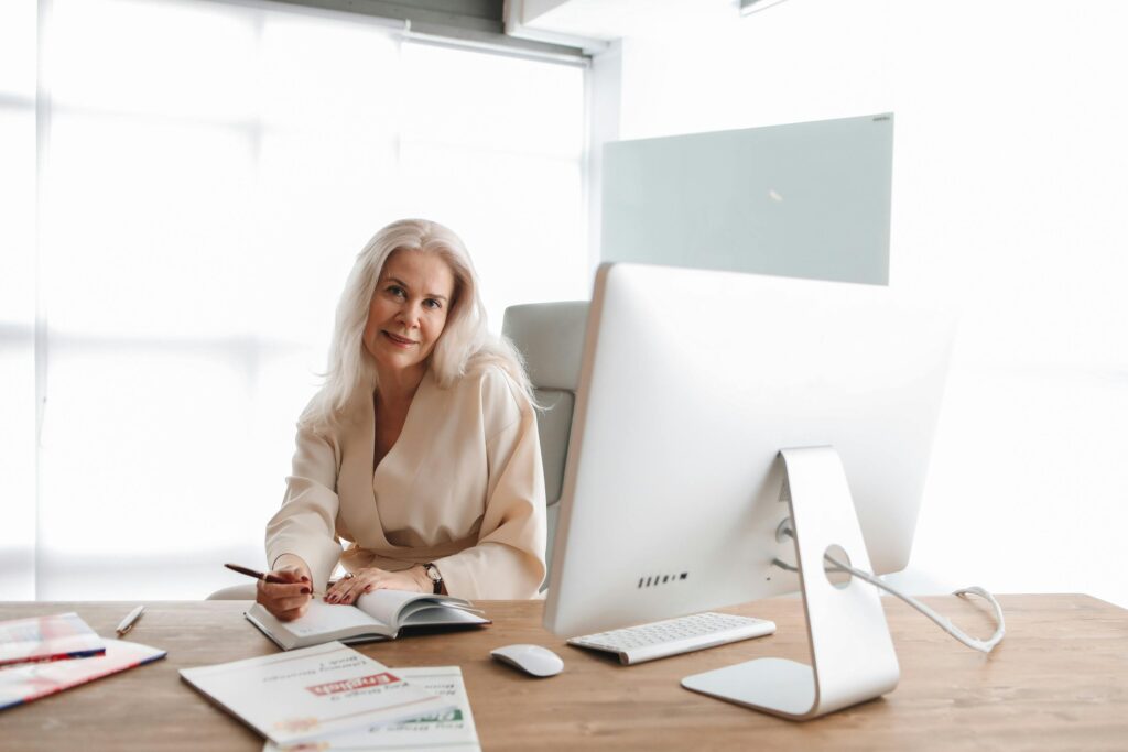 A professional woman working at a computer and writing notes in an office, symbolizing career opportunities and job growth after studying in Denmark.