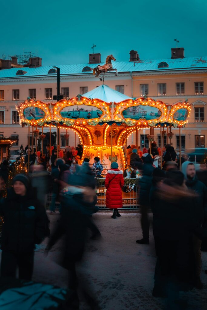 International students exploring a vibrant winter market in Helsinki, Finland with a glowing carousel and festive crowd atmosphere
