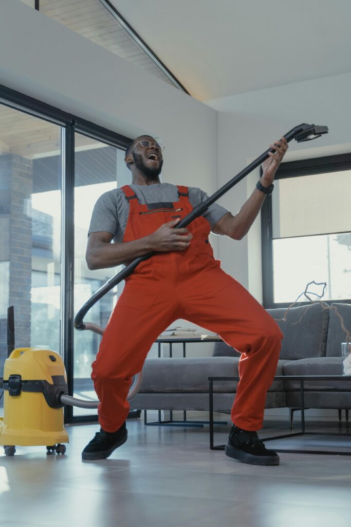 A cheerful worker wearing red overalls cleaning indoors, representing part-time job opportunities and a positive work-life balance in Australia.