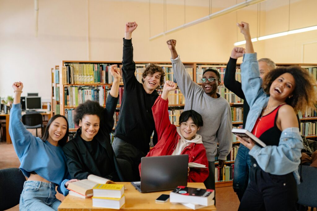 Group of diverse international students smiling and celebrating success in a university library in Australia