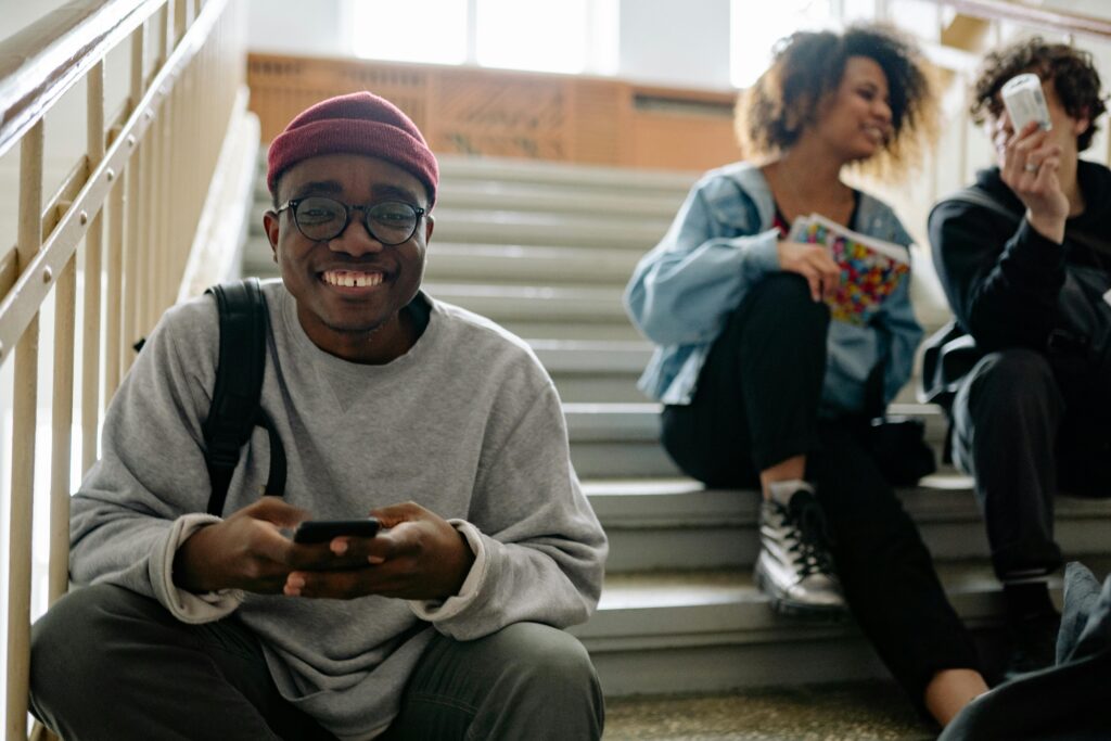 Happy international students using mobile phone on campus while planning to study in Ireland