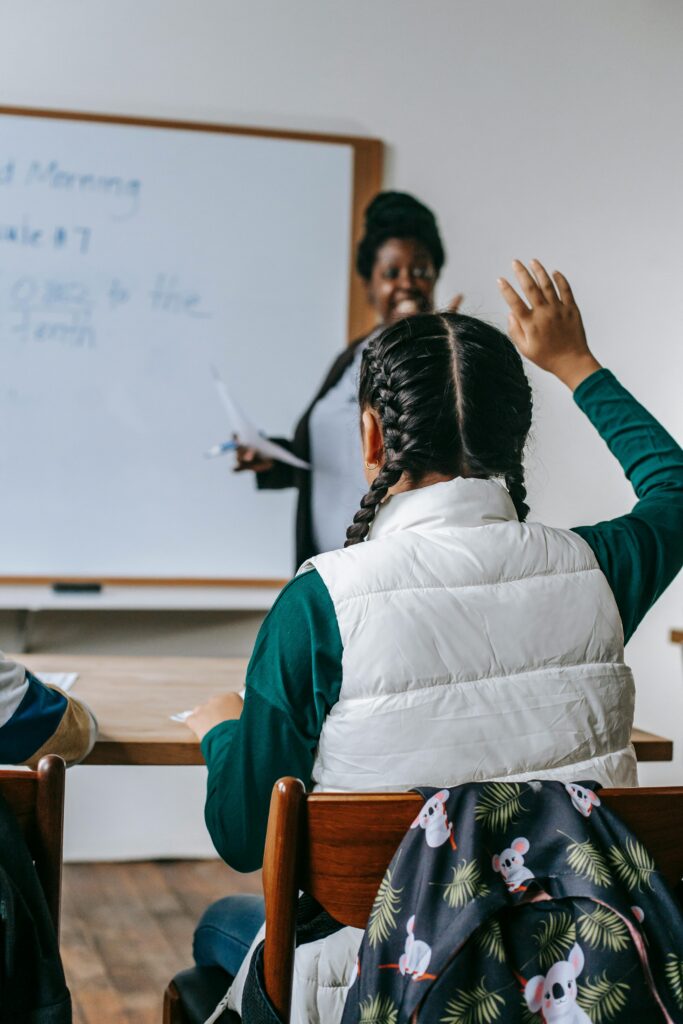 Student raising hand in classroom asking questions about study options after 12th.